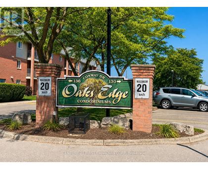 A sign for Oak's Edge Condominiums is displayed in front of a building.