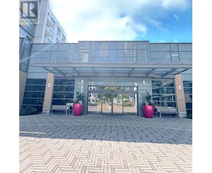 A modern building entrance with glass doors and two large pink planters.