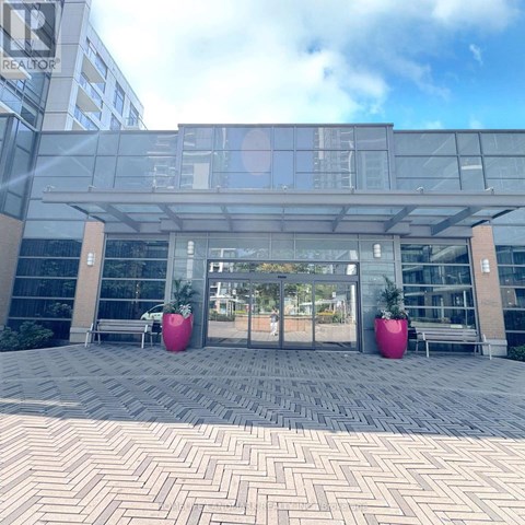 A modern building entrance with glass doors and two large pink planters.