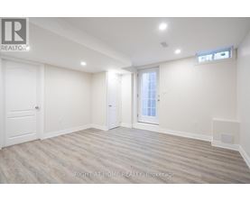 A spacious room with wood flooring and white walls.