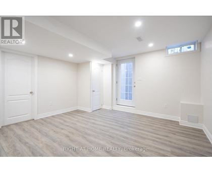 A spacious room with wood flooring and white walls.