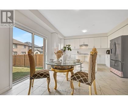 A dining room with a glass table and chairs with a view of a backyard.
