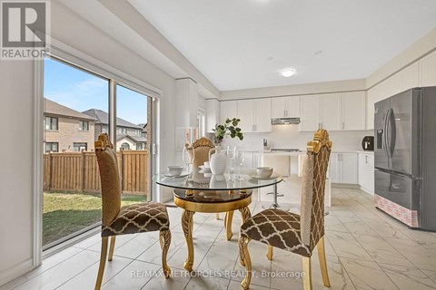 A dining room with a glass table and chairs with a view of a backyard.