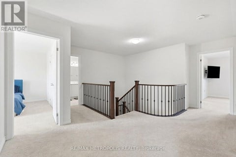 A spacious room with a staircase and a flat screen TV.