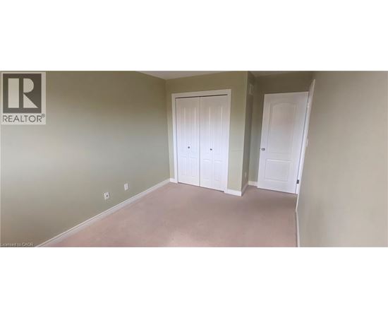 A room with two white doors and a realtor logo on the wall.