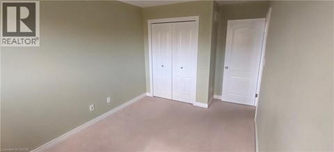 A room with two white doors and a realtor logo on the wall.
