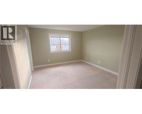 A bedroom with a window and carpeted floor.