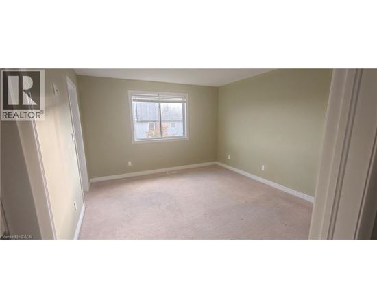 A bedroom with a window and carpeted floor.