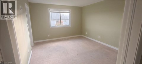 A bedroom with a window and carpeted floor.