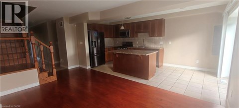 A kitchen with brown cabinets and a black refrigerator.