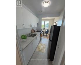 A kitchen with white cabinets and a black refrigerator.