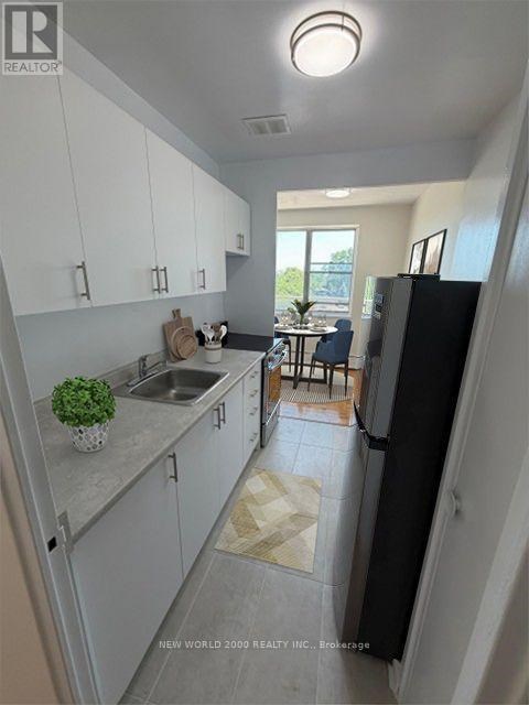 A kitchen with white cabinets and a black refrigerator.