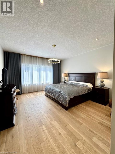 A bedroom with a large bed and wooden flooring.