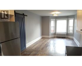 A room with a refrigerator, a table, and a window.
