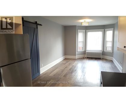 A room with a refrigerator, a table, and a window.
