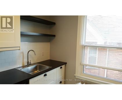 A kitchen with a sink and a window with blinds.