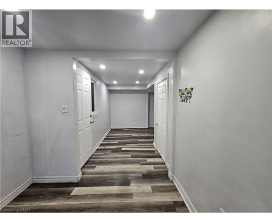 A hallway with wooden flooring and white walls.