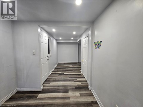 A hallway with wooden flooring and white walls.