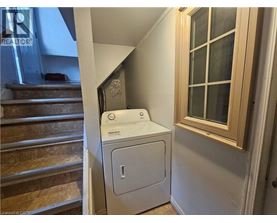 A white dryer is sitting next to a window in a small room.