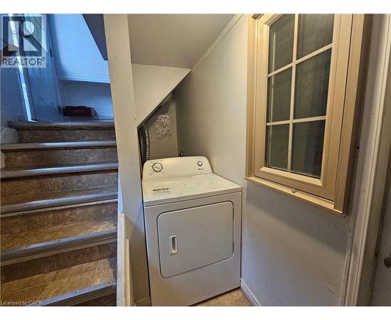 A white dryer is sitting next to a window in a small room.