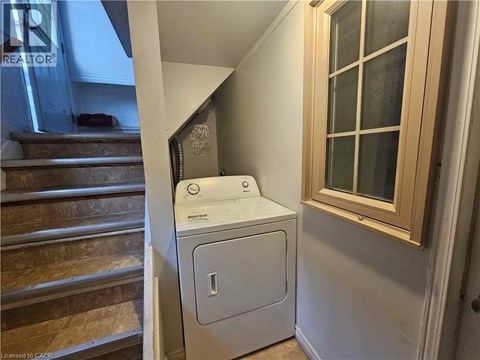 A white dryer is sitting next to a window in a small room.