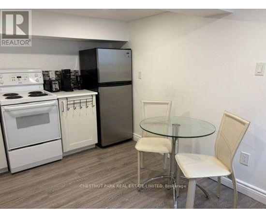 A kitchen with a white stove, white oven, and a glass table with two chairs.