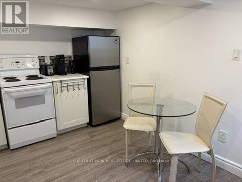 A kitchen with a white stove, white oven, and a glass table with two chairs.