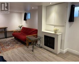 A living room with a red couch, a glass table, and a fireplace.
