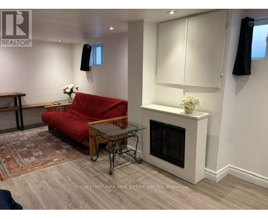 A living room with a red couch, a glass table, and a fireplace.