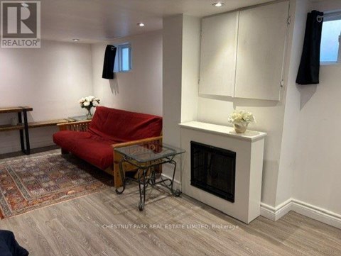 A living room with a red couch, a glass table, and a fireplace.