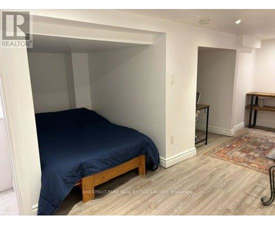 A bedroom with a bed, wooden frame, and a rug on the floor.