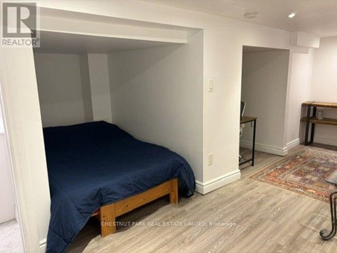 A bedroom with a bed, wooden frame, and a rug on the floor.
