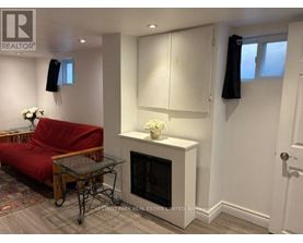 A living room with a red couch, a glass coffee table, and a fireplace.
