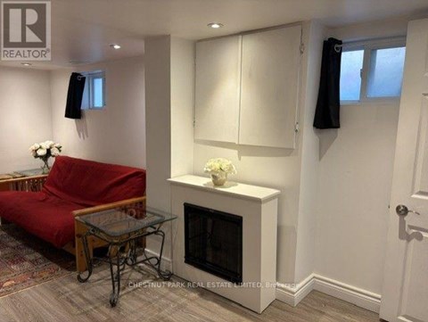 A living room with a red couch, a glass coffee table, and a fireplace.