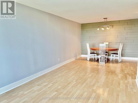 A dining room with a wooden floor and a table with chairs.
