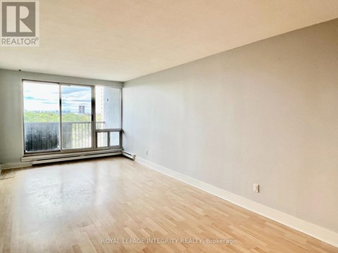 A room with a large window and wooden flooring.