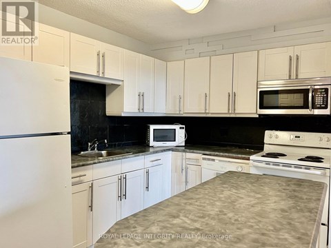 A kitchen with white cabinets and black countertops.