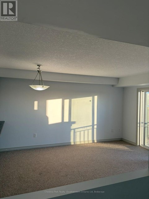 A room with a carpet floor and a hanging light fixture.