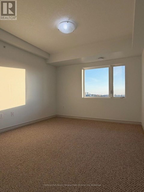 A room with a carpeted floor and a window overlooking the beach.