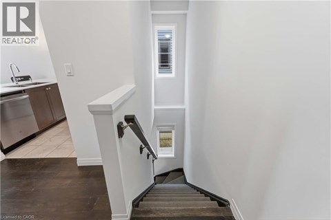 A staircase with a white railing and a window in the distance.