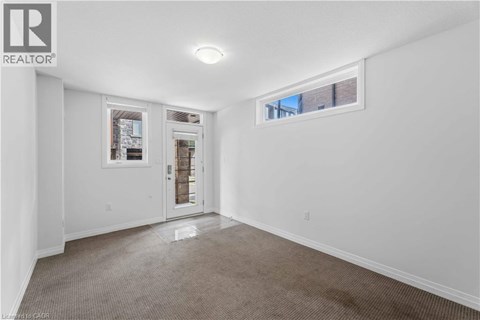 A room with a carpeted floor and a window with a view of a building outside.