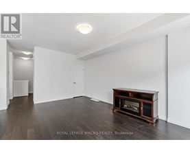 A spacious room with a fireplace and wooden flooring.
