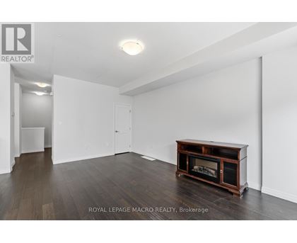 A spacious room with a fireplace and wooden flooring.