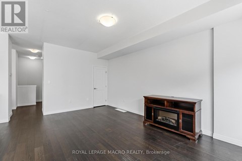 A spacious room with a fireplace and wooden flooring.