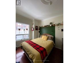 A bedroom with a bed covered in a yellow and red comforter.