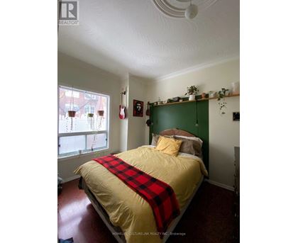 A bedroom with a bed covered in a yellow and red comforter.