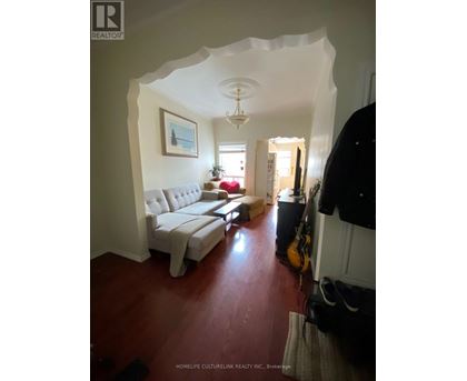 A living room with a white couch and a guitar leaning against the wall.