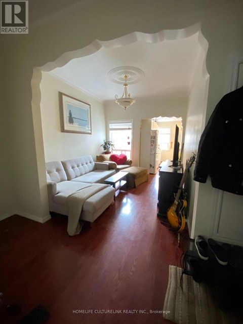 A living room with a white couch and a guitar leaning against the wall.