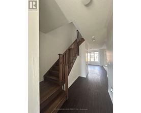 A staircase with a wooden handrail and steps leads to a doorway.