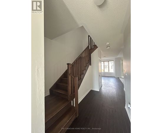 A staircase with a wooden handrail and steps leads to a doorway.